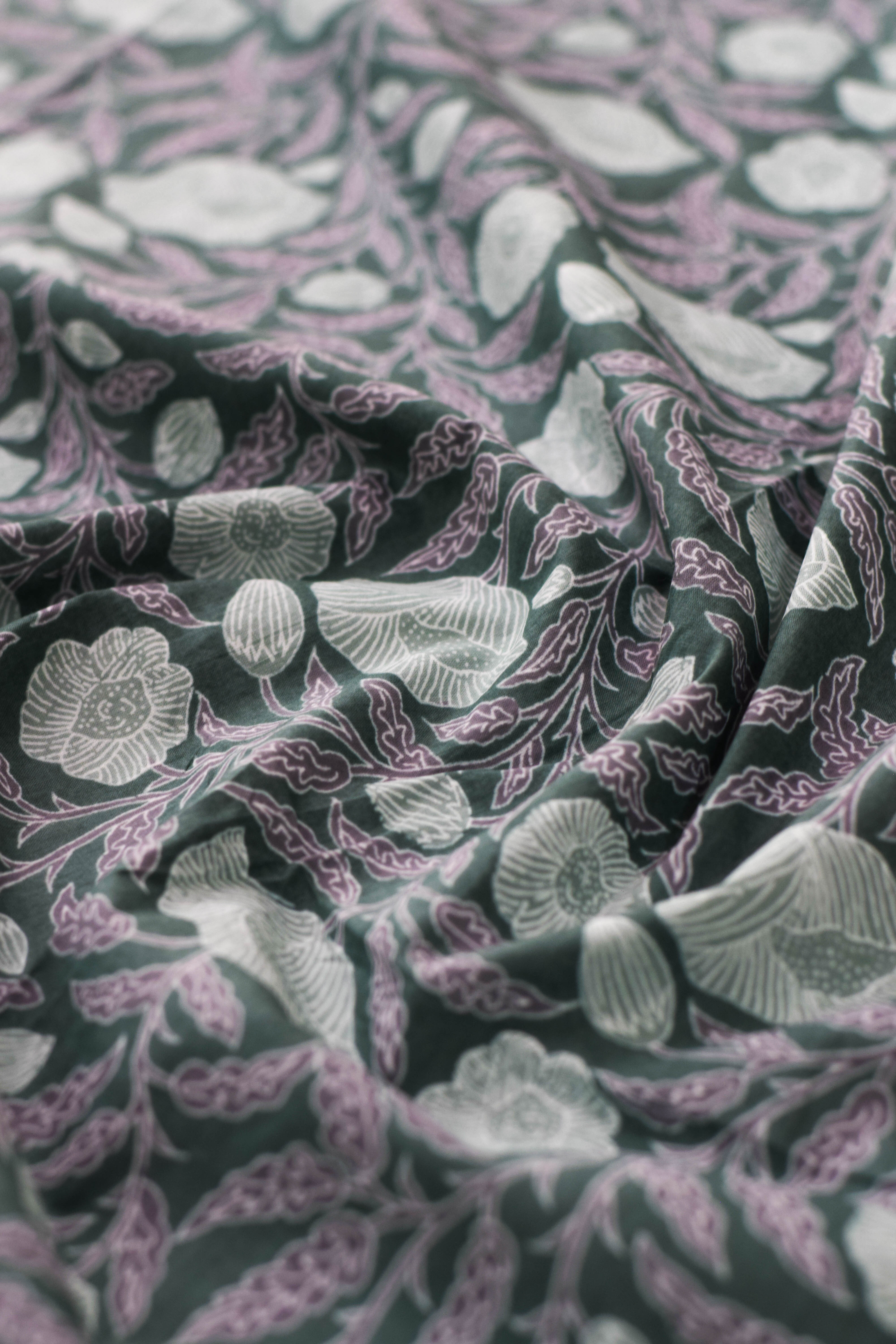 Close-up of floral patterned fabric in green, purple, and white.