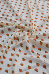 Fabric with small orange floral pattern on white background