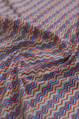 Close-up of zigzag patterned fabric in red, blue, and beige.