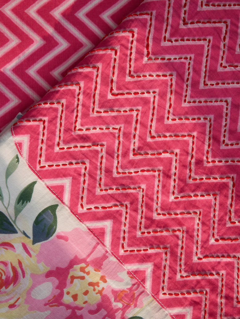 Close-up of pink zigzag patterned fabric with floral fabric partially visible underneath.