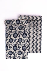 Two pieces of fabric, one with a blue floral pattern on a grey background and another with a blue chevron pattern on a grey background, both displayed against a white background.