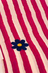 Striped fabric with a blue flower and yellow center on a red and beige background