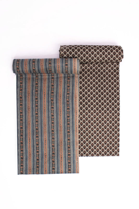 Two pieces of fabric, one with horizontal rust and blue stripes and another with a brown geometric buti pattern, likely representing a suit set and a dupatta.