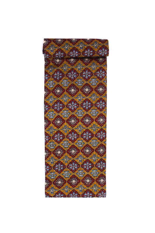 Fabric with a floral medallion pattern in red, blue, and gold on a mustard base.