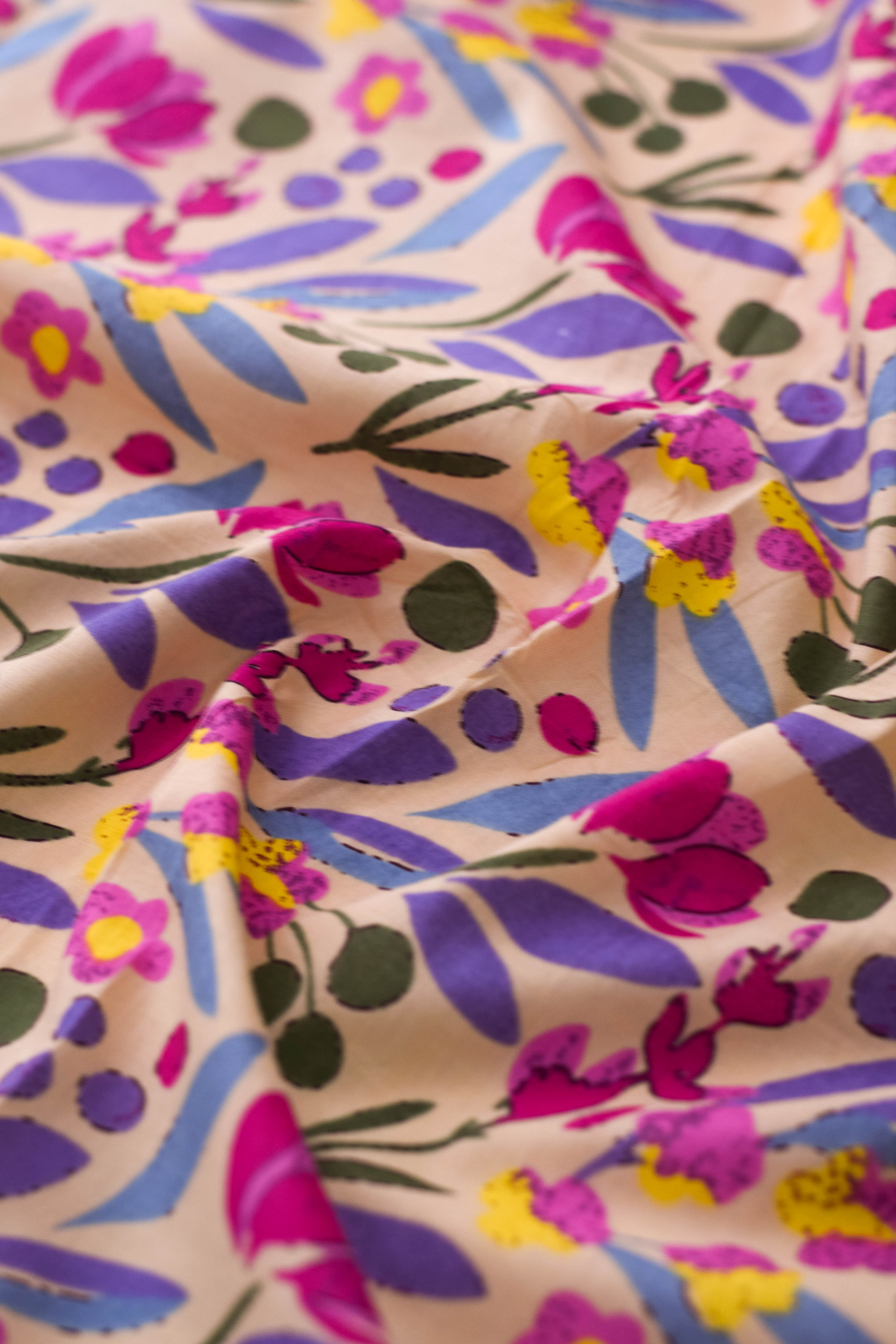 Close-up of floral patterned fabric with pink, purple, and yellow colors.