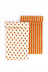 Two pieces of fabric with geometric patterns. One has a series of red and blue diamond shapes on a beige background, and the other has a striped pattern with orange colors.