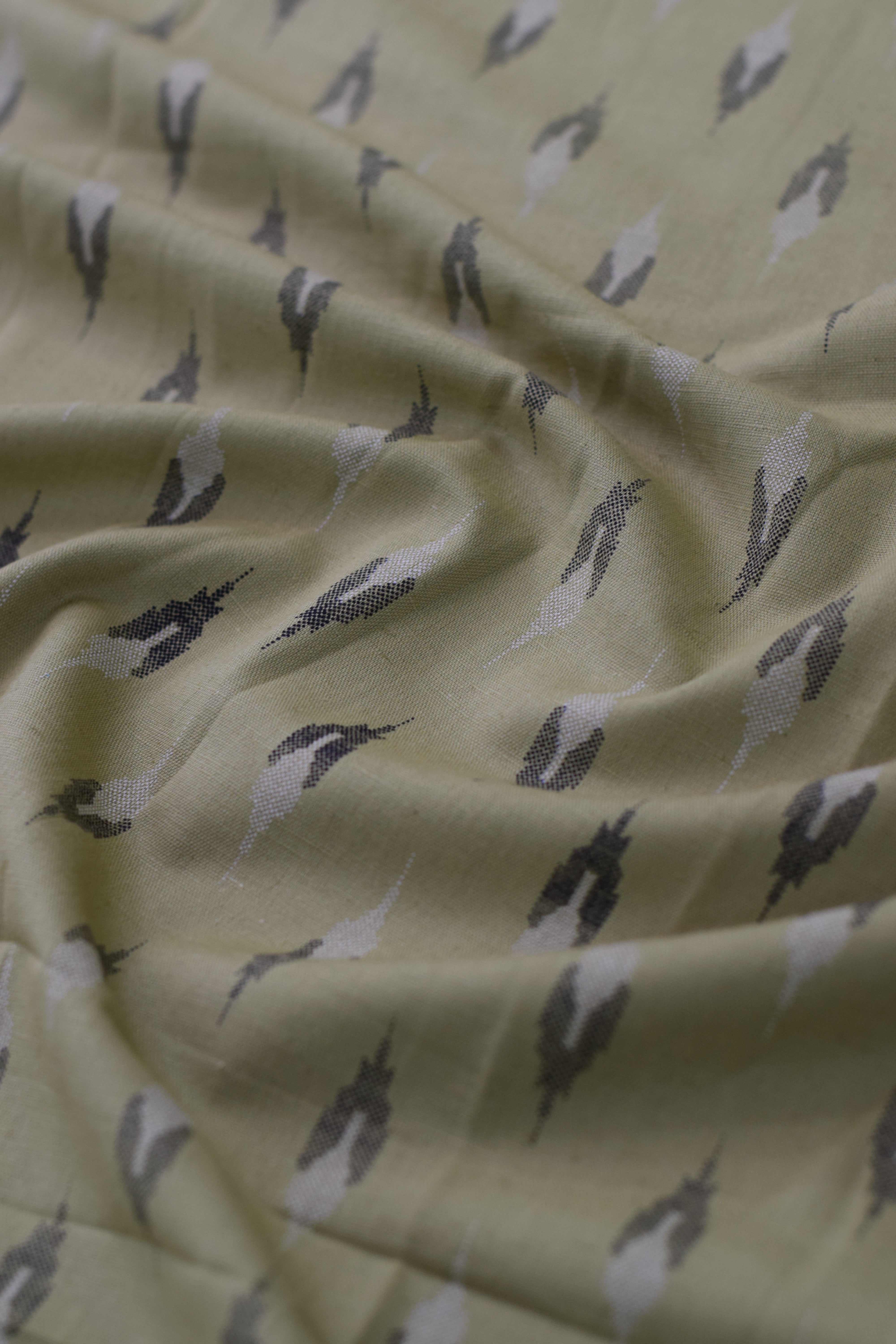 Close-up of fabric with bird pattern on light yellow background