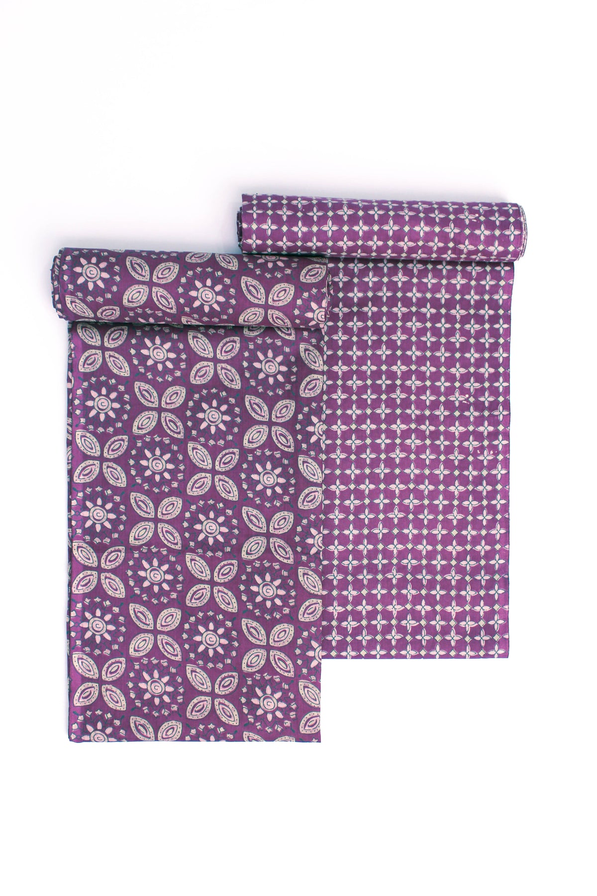 A rolled-up fabric with orange, green, and cream geometric patterns on a purple base, along with stylized floral designs.