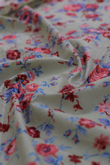 Close-up of floral patterned fabric in red, blue, and pink on a white background.
