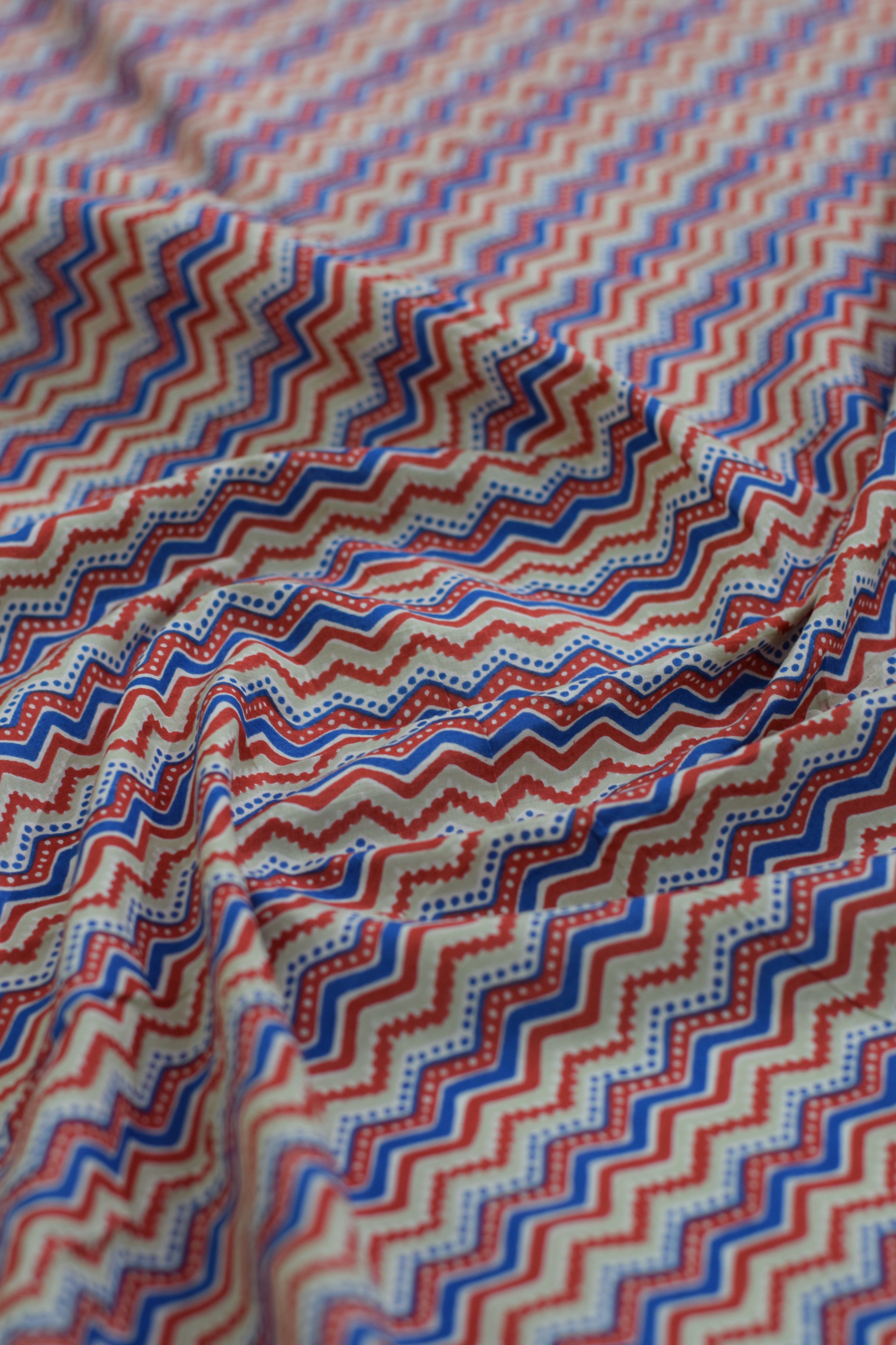 Close-up of zigzag patterned fabric in red, blue, and beige.