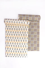 Two pieces of fabric, one with a golden blossom pattern and another with a geometric mosaic print, both in beige, blue, and golden colors.