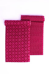 Two folded pieces of fabric with Bandhej-inspired patterns, one in pink and the other in a darker shade, possibly red, laid flat on a white background.