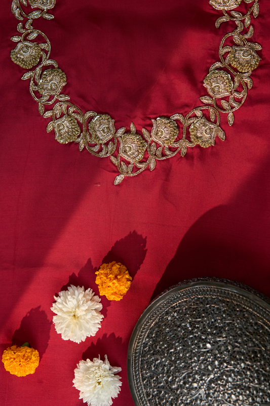 Decorative gold embroidery on maroon fabric 