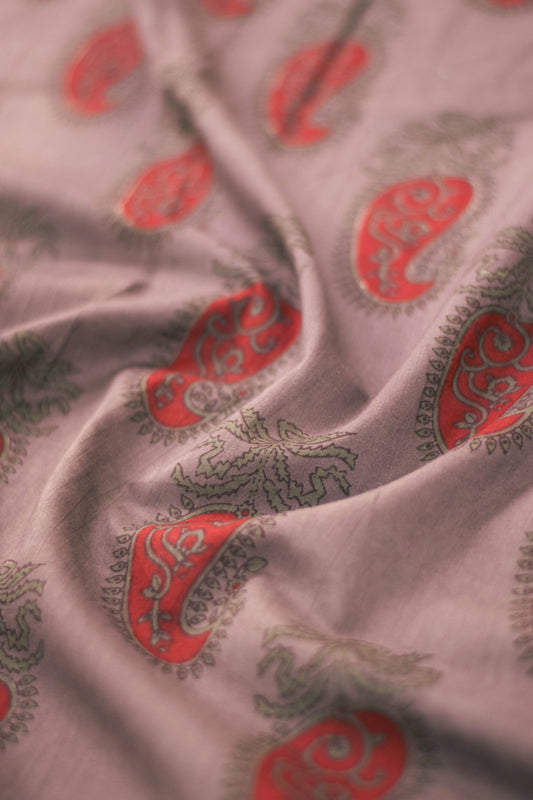 Close-up of paisley patterned fabric in red and green on a light background.