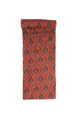 A swatch of fabric with a maroon background featuring intricate blue and olive floral accents.