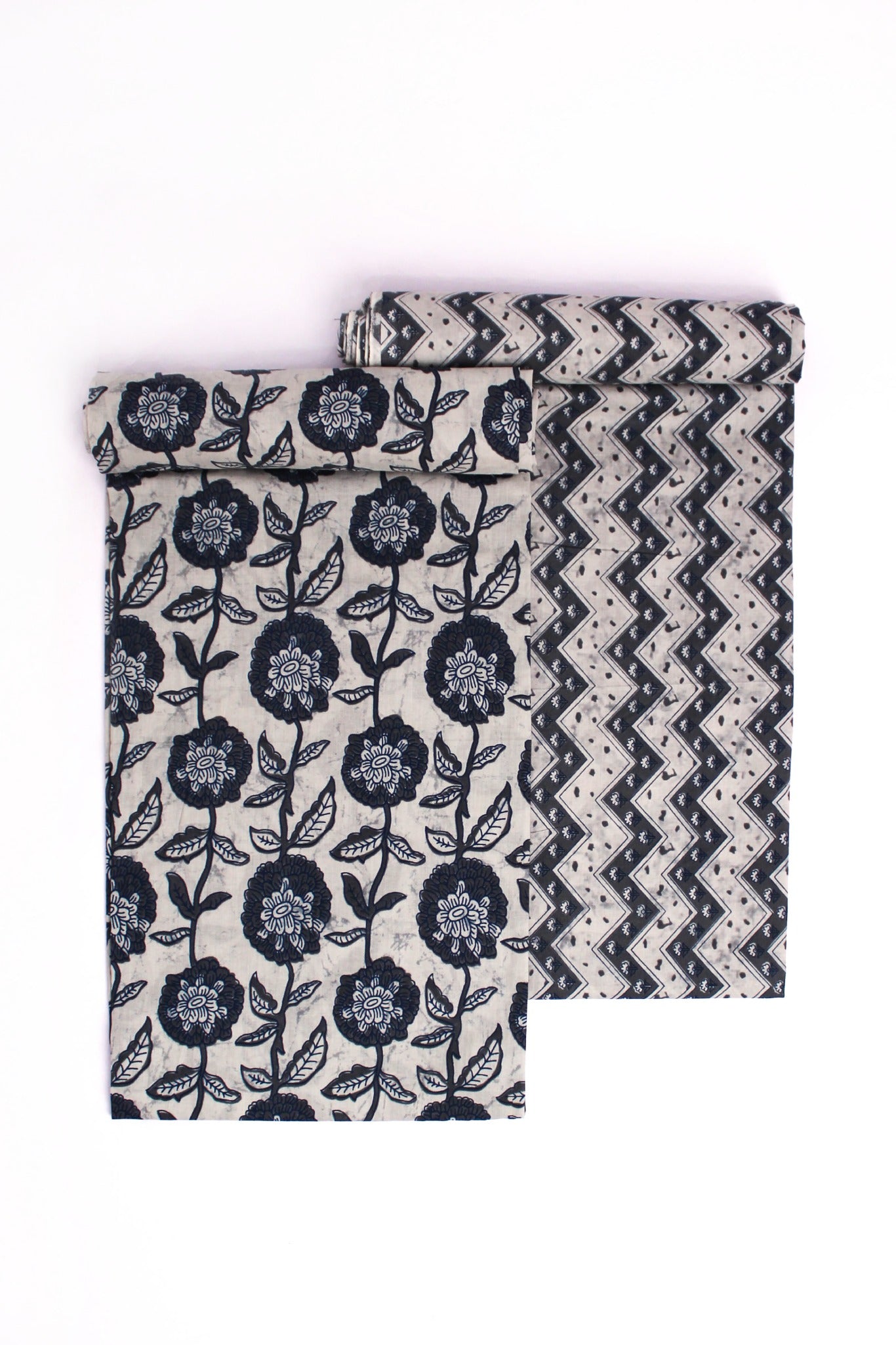 Two pieces of fabric, one with a blue floral pattern on a grey background and another with a blue chevron pattern on a grey background, both displayed against a white background.