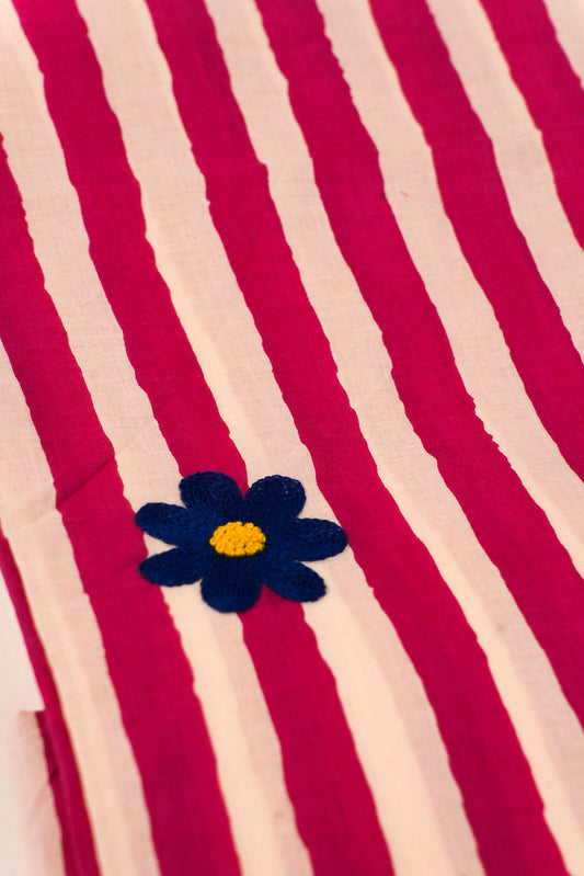 Striped fabric with a blue flower and yellow center on a red and beige background