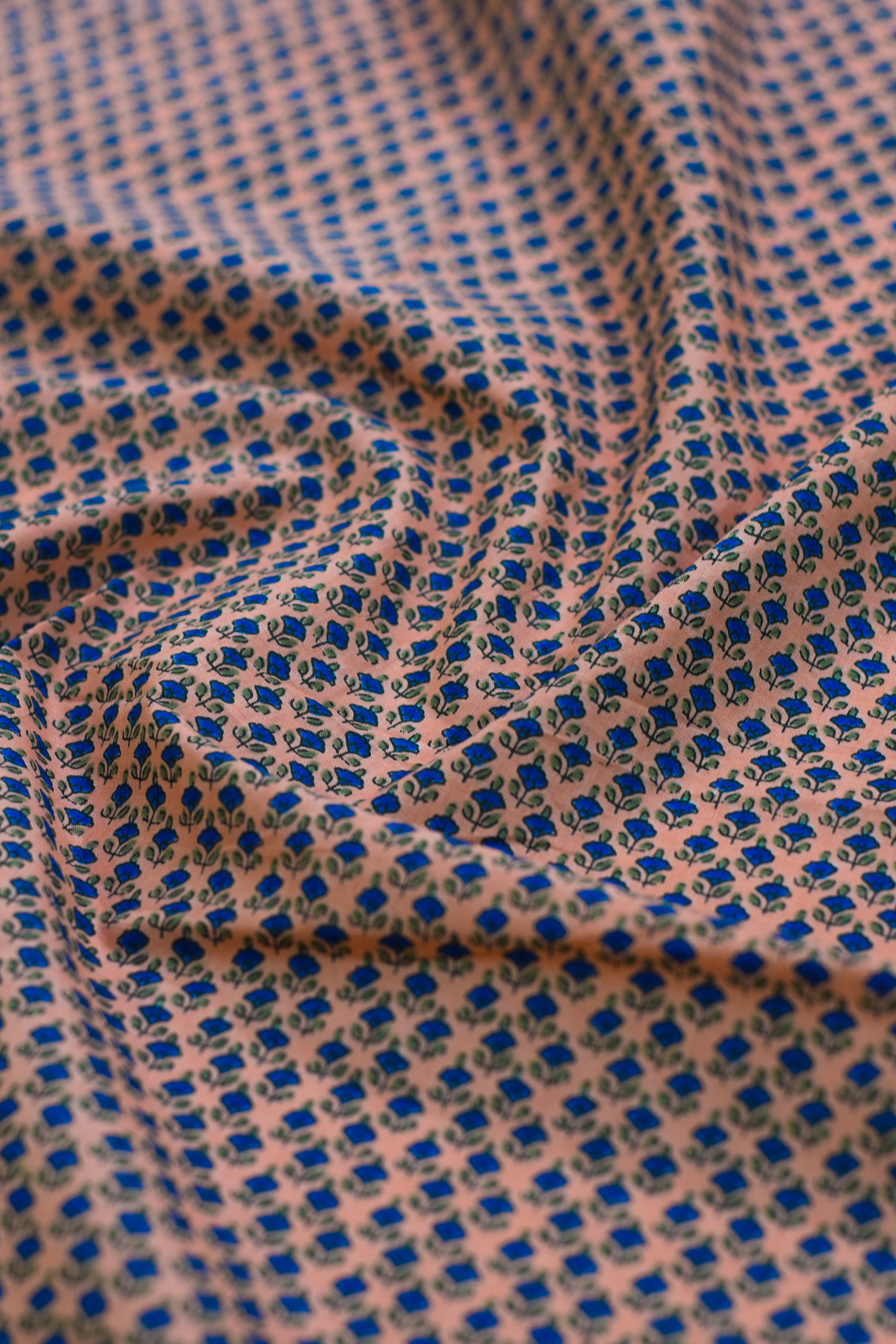 Close-up of fabric with blue and green pattern on a pink background