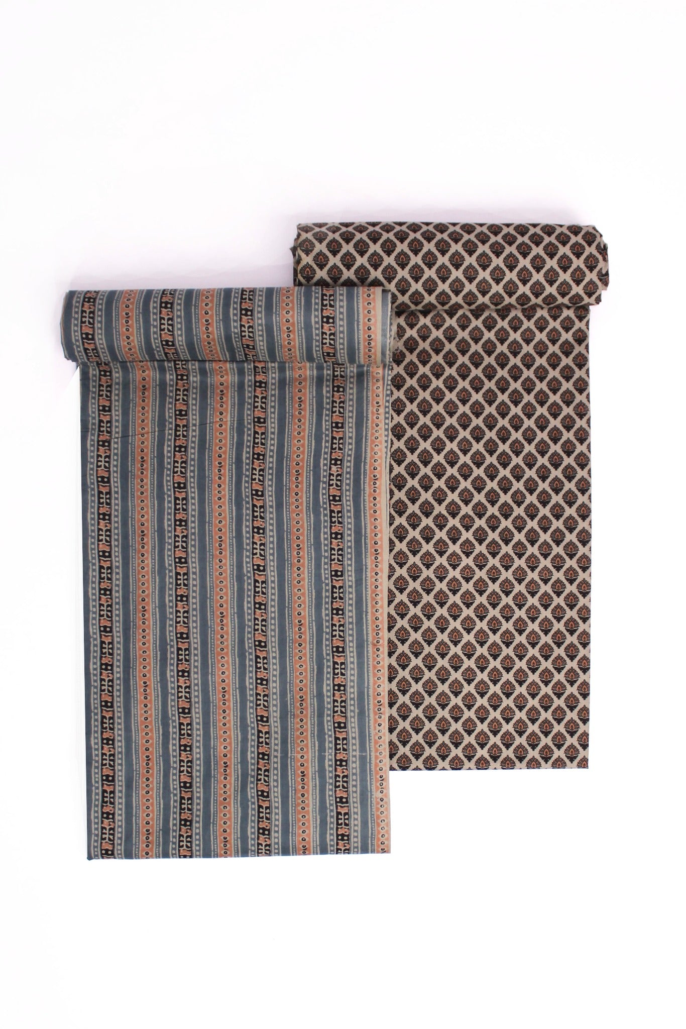 Two pieces of fabric, one with horizontal rust and blue stripes and another with a brown geometric buti pattern, likely representing a suit set and a dupatta.