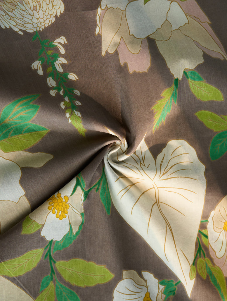 Floral fabric with green leaves and white flowers on a brown background