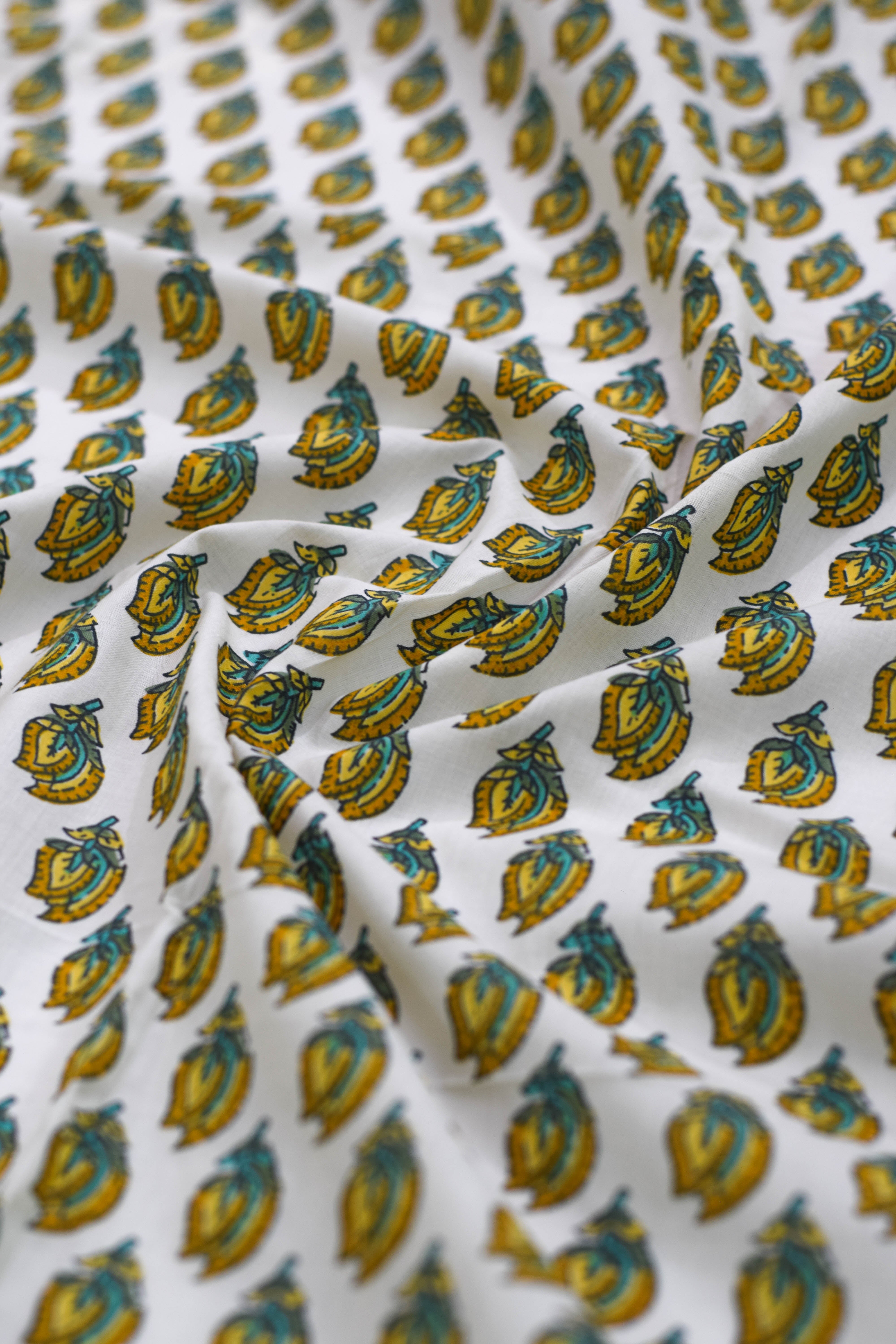 Close-up of patterned fabric with blue and yellow designs on a white background.