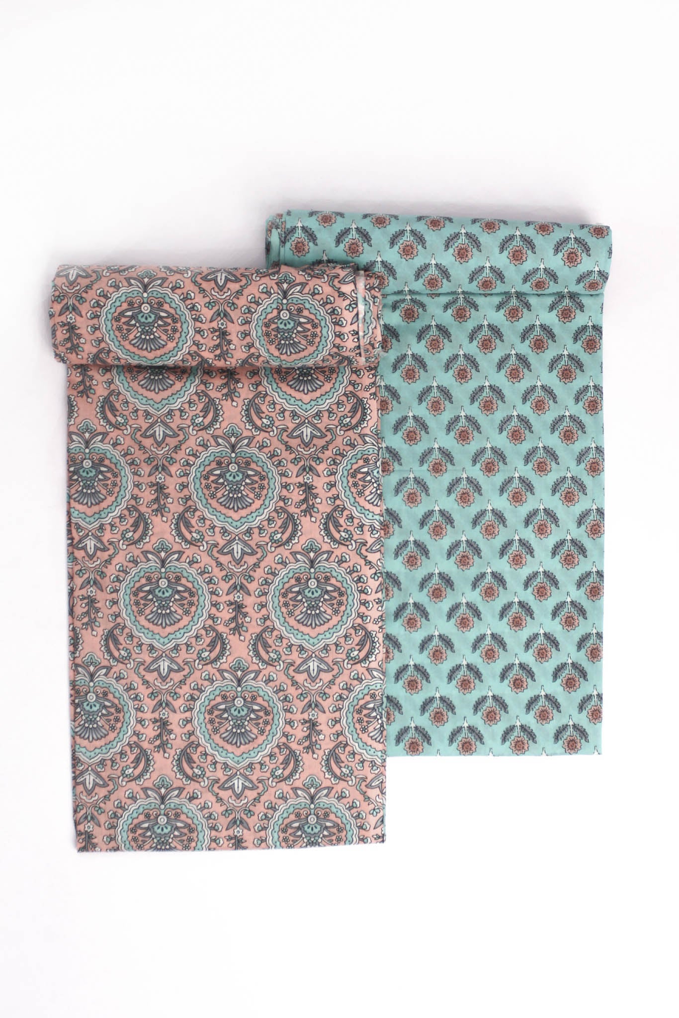 Two pieces of fabric, one with a turquoise base and floral motifs, and the other with a peach Mughal-inspired jaal design.