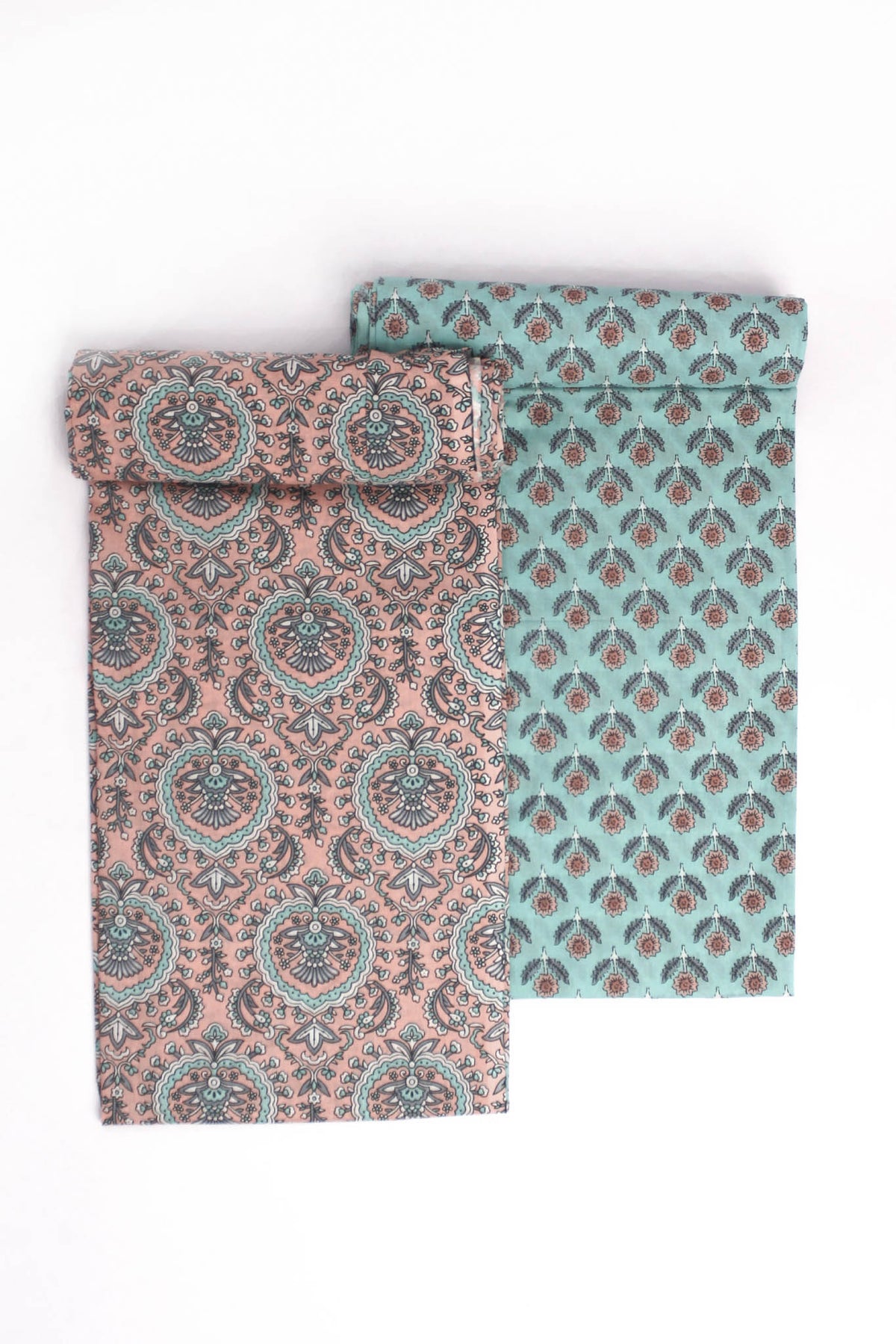 Two pieces of fabric, one with a turquoise base and floral motifs, and the other with a peach Mughal-inspired jaal design.