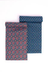 Two pieces of fabric with floral patterns, one with a dark navy background and another with a lighter blue background, both featuring red and yellow tulip motifs.