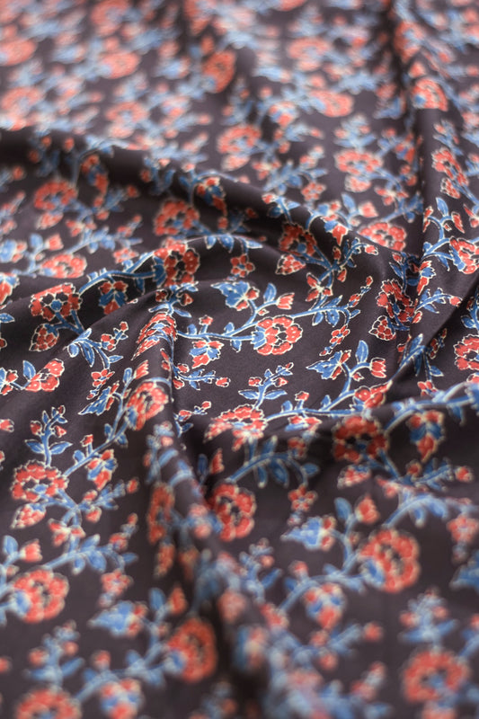 Floral patterned fabric with red and blue colors on a black background.