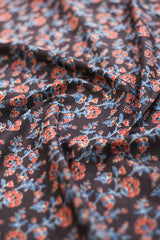 Floral patterned fabric with red and blue colors on a black background.